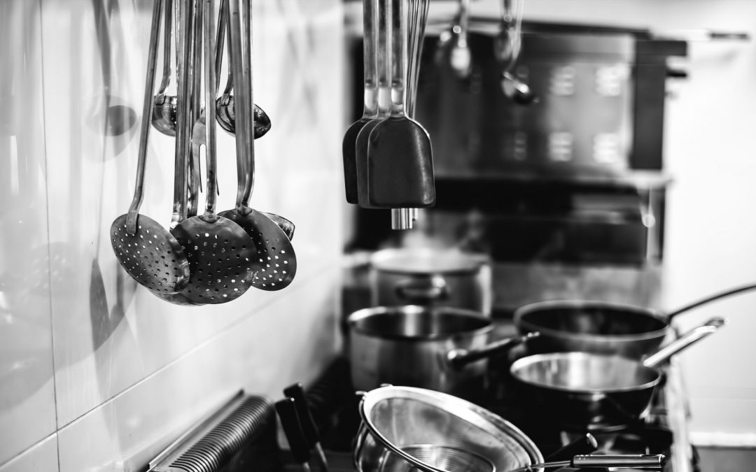 A well-organized kitchen with various pots and pans suspended from the wall, highlighting a practical culinary environment.